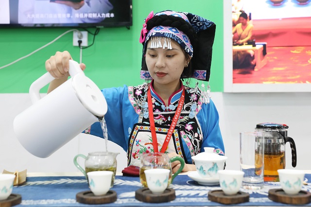 9月6日，在中国农加会F展厅，一名身着少数民族服饰的展商在沏茶。何五昌 摄.JPG